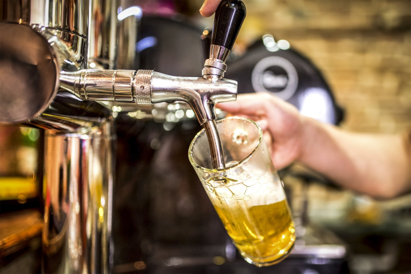 barman hand at beer tap pouring a draught lager beer serving in a restaurant or pub