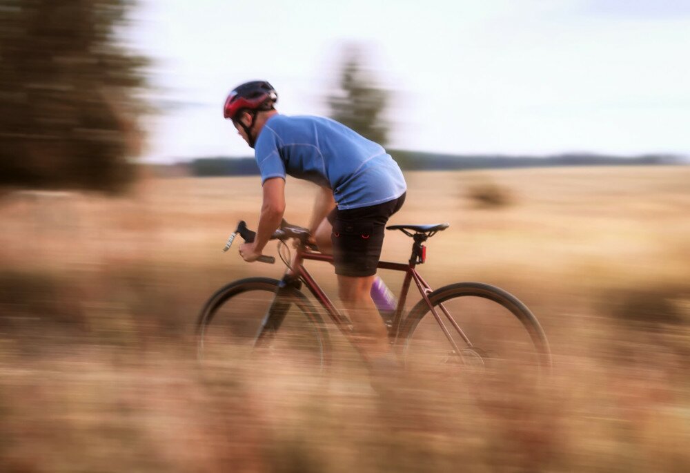 Cyclist in motion. Young sporty man rides gravel bike along the trail in the field. Blurred motion. Selective focus