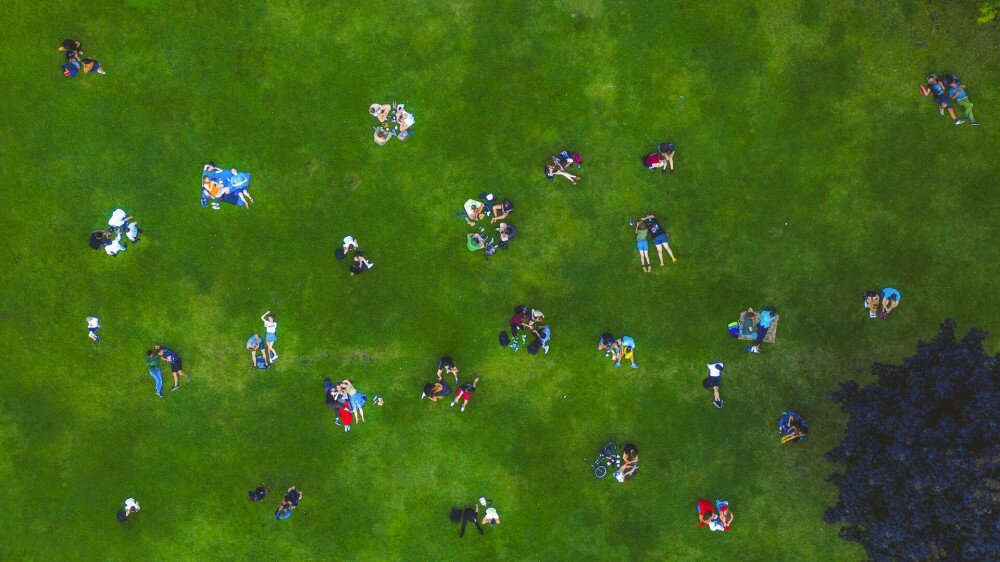 Top View Many people rest on a green lawn. Drone Photo 90 degrees. Social distance while relaxing on the lawn after quarantine.