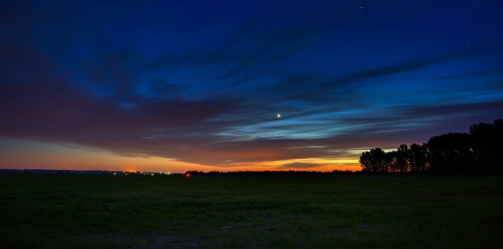 Venus in the night sky with stars. A bright sunset with clouds. Cosmic space above the earth's surface. Long exposure.