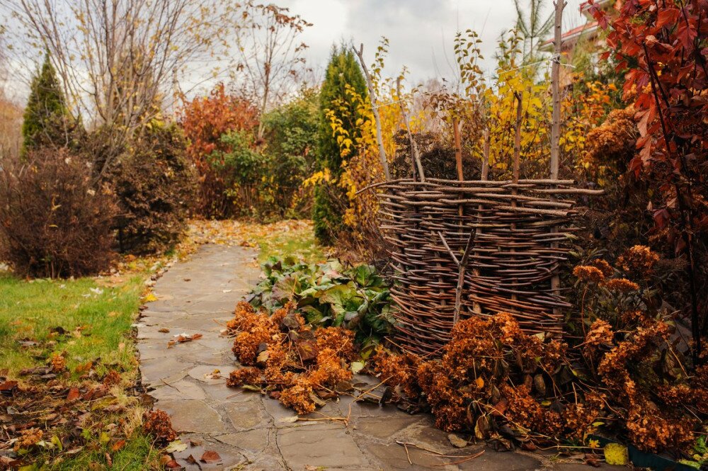 Walking in november garden. Late autumn view with rustic fence and stone pathway
